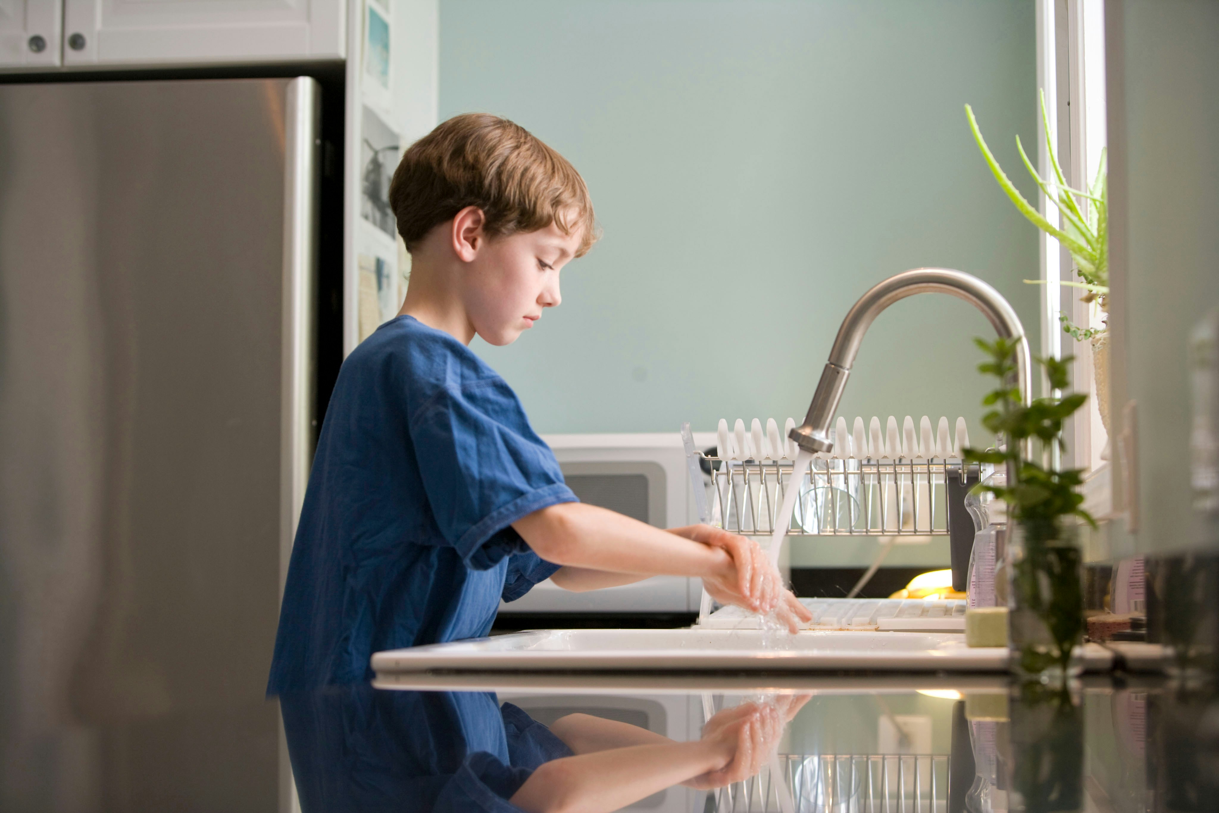child washing hands at kitchen sink